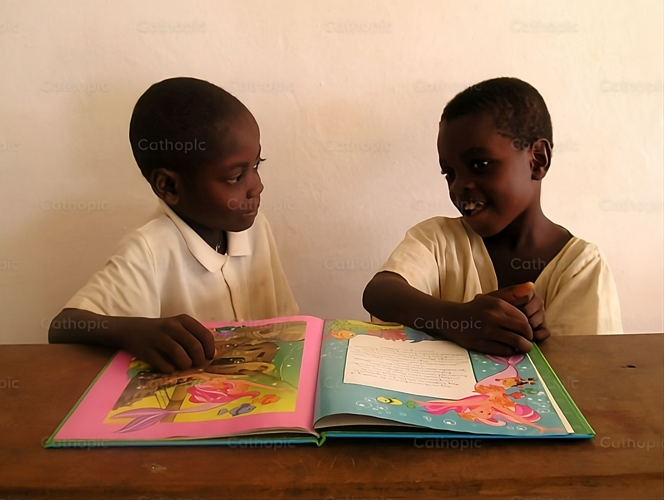 Two kids learning with a colorful book.