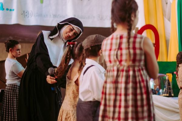 Photo of nun smiling and interacting with children. Kids learning.