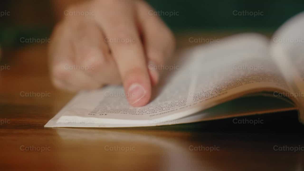 Leyendo biblia sobre una mesa con el dedo - Banco de vídeos católicos