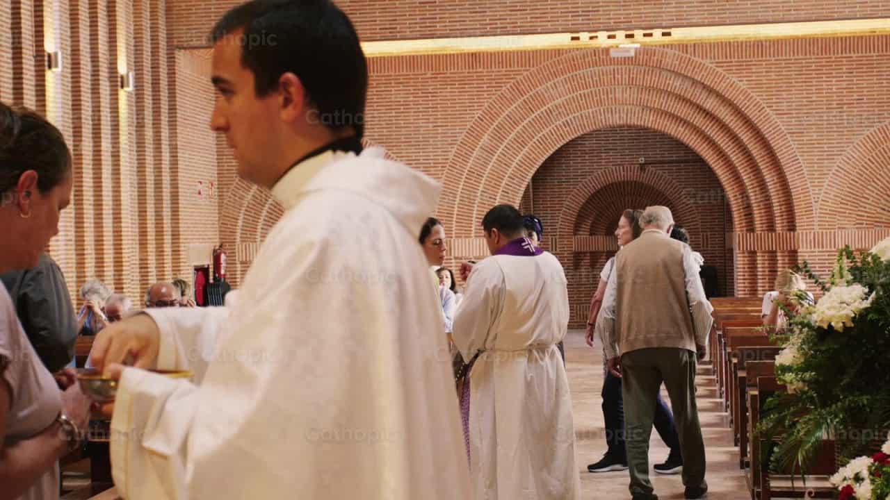 Sacerdote dando la Sagrada Comunion - Banco de vídeos católicos - Fotografía por Almures Studio