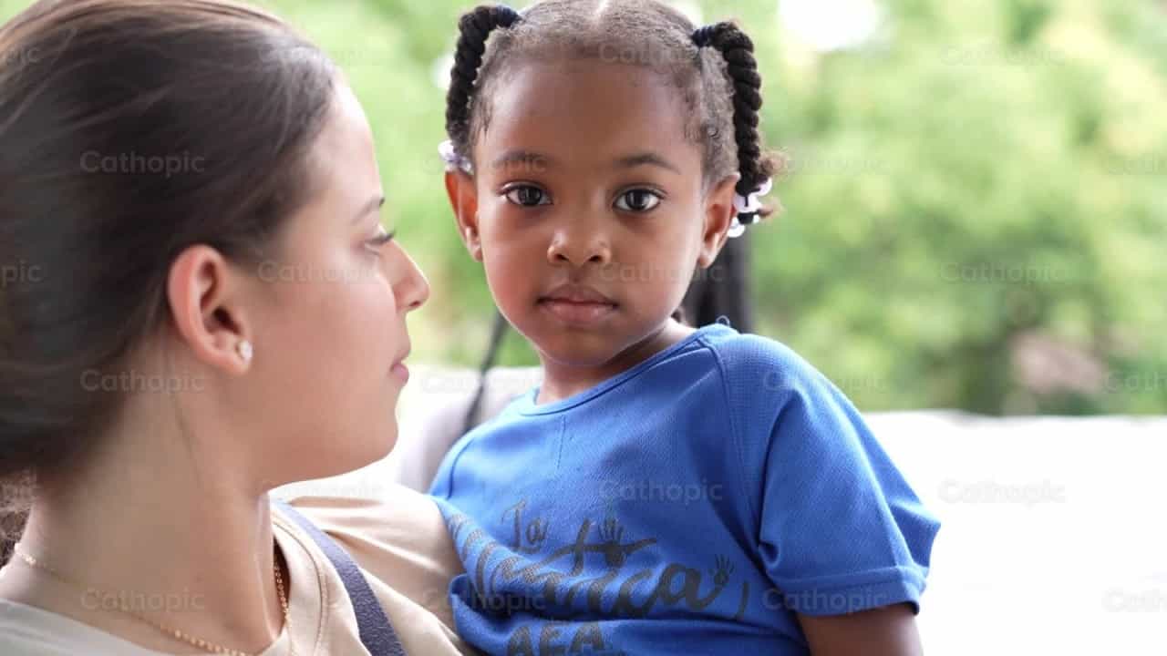 Ragazza con trecce tra le braccia di un missionario - Video stock cattolici - Foto di Iván W. Jaques