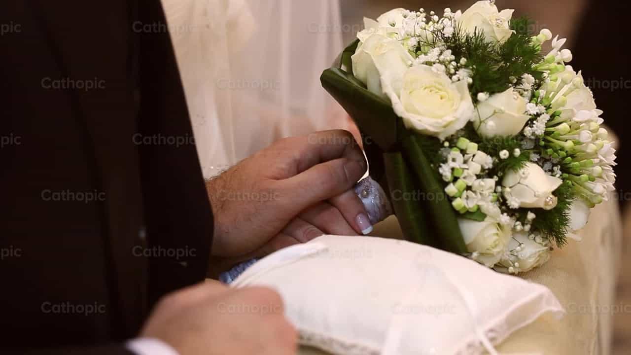 Manos intercambiando anillos durante una boda católica - Banco de vídeos católicos