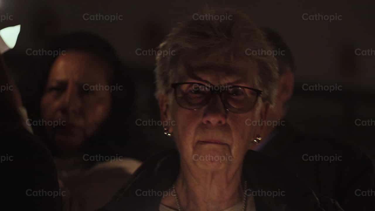Mujer encendiendo una vela en el Fuego Sagrado - Banco de vídeos católicos - Fotografía por Almures Studio