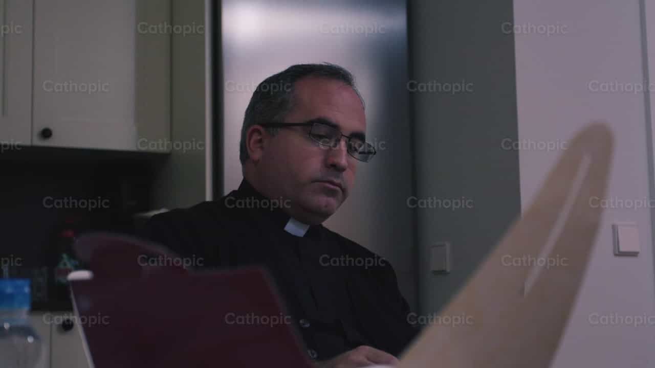 Sacerdote en la cocina esperando la comida del dia - Banco de vídeos católicos