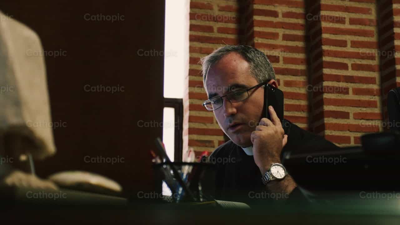 Sacerdote atendiendo llamada telefonica - Banco de vídeos católicos - Fotografía por Almures Studio