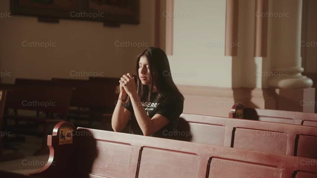 Jovencita orando arrodillada en el templo - Banco de vídeos católicos