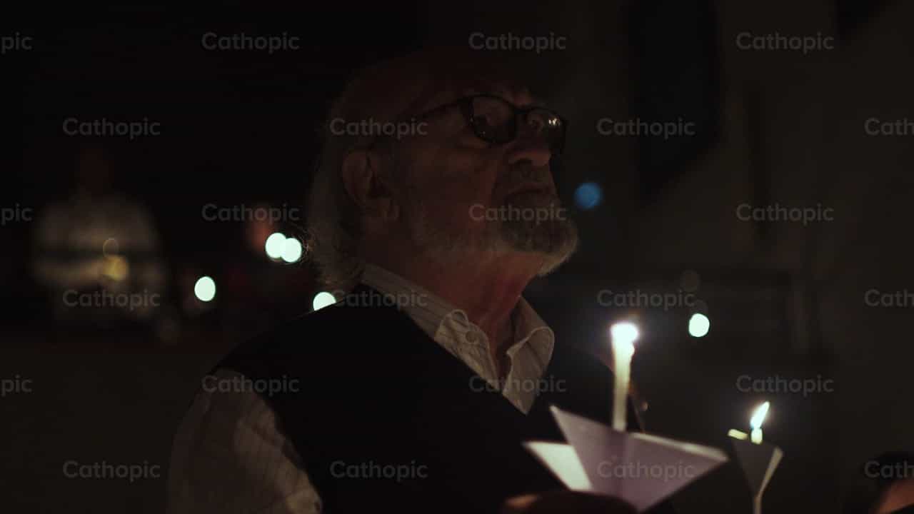 Hombre rezando con una vela encendida - Banco de vídeos católicos - Fotografía por Almures Studio