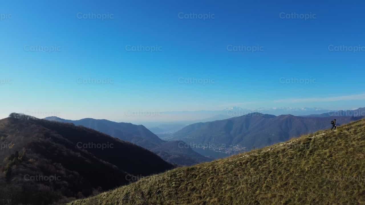 Hombre caminando hacia la cima de la montaña - Banco de vídeos católicos - Fotografía por Frames Cristianos