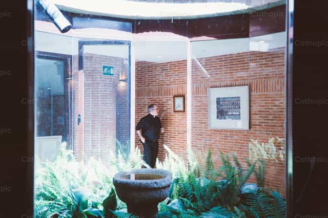 Sacerdote caminando hacia la oficina parroquial - Banco de imágenes católicas - Fotografía por Almures Studio