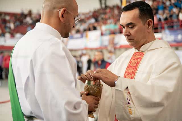 Prêtre avec le calice pendant la célébration eucharistique - Images catholiques de stock