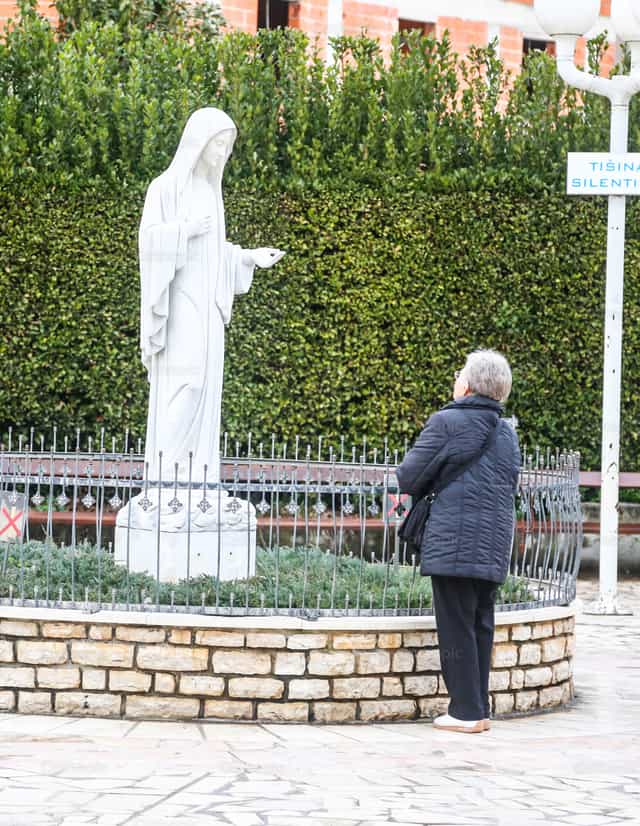 Vrouw biddend voor een standbeeld van de Heilige Maagd Maria - Katholieke stockfoto's