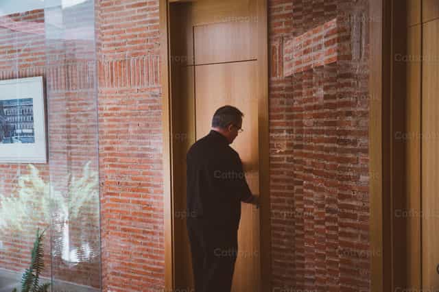 Sacerdote entrando a la oficina parroquial - Banco de imágenes católicas - Fotografía por Almures Studio