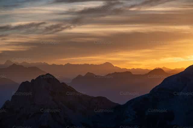 Cruz en la cima al atardecer, en medio de la majestad de la Creación. - Banco de imágenes católicas