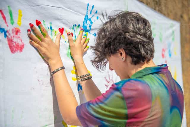 Hands with colorful paint leaving prints on a white cloth during an art event - Catholic stock images - Photo by Pierluigi Palazzi