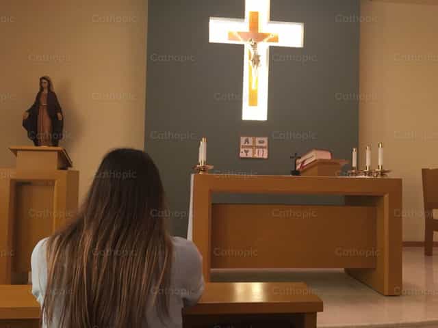 Vrouw in een kapel biddend - Katholieke stockfoto's