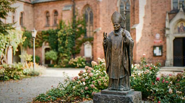 Extérieur d’église avec statue en bronze du pape Jean-Paul II - Images catholiques de stock - Photo de Noemí Márquez