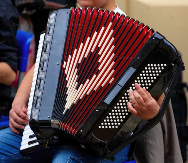 Músico tocando el acordeón rojo y negro durante un concierto callejero - Banco de imágenes católicas - Fotografía por Antonio Gravante