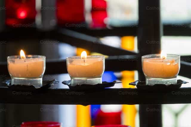 Fila de velas en el interior de una iglesia para la devoción o la oración - Banco de imágenes católicas - Fotografía por Joan Sutter