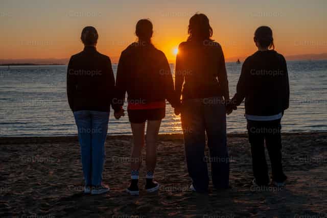 Amigos en la playa viendo el amanecer - Banco de imágenes católicas