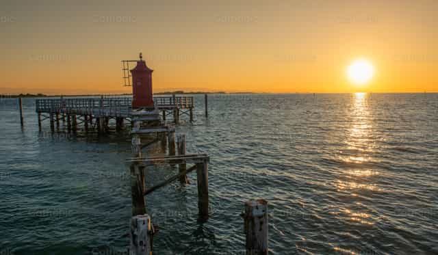 The old red lighthouse of Lignano Sabbiadoro at sunrise - Catholic stock images - Photo by Pierluigi Palazzi
