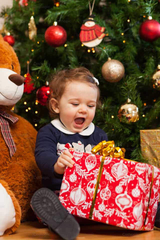 Niña pequeña con regalos cerca del árbol de Navidad. - Banco de imágenes católicas - Fotografía por Antonio Gravante
