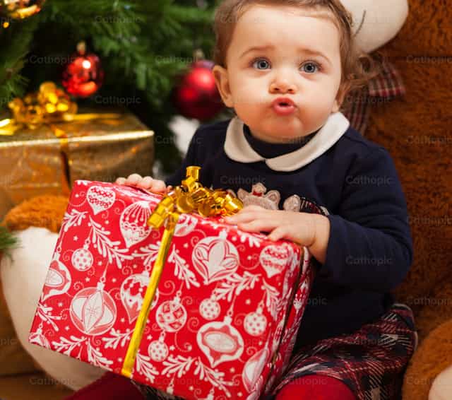 Toddler girl with gifts near christmas tree - Catholic stock images - Photo by Antonio Gravante