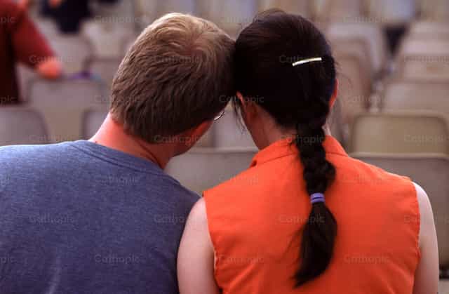 Couple sits, heads together - Banco de imágenes católicas - Fotografía por Joan Sutter