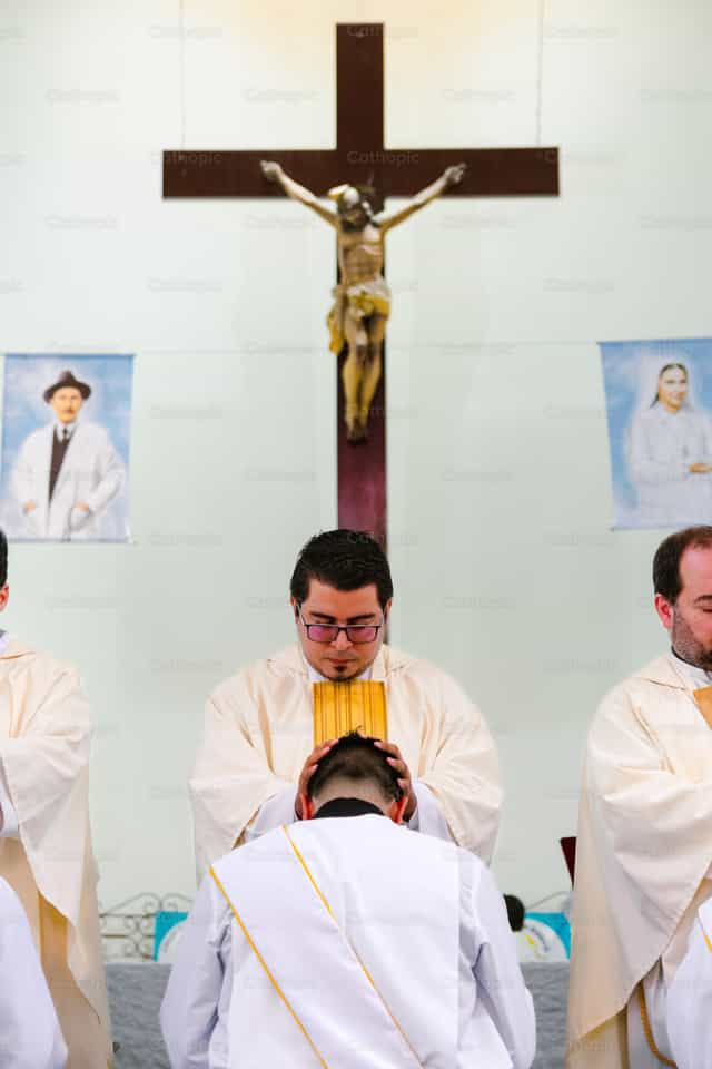 O sacerdote ora pelo diácono e Jesus o abençoa - Imagens católicas de stock