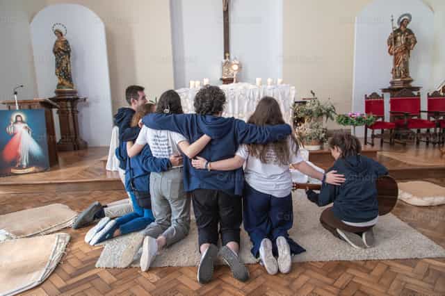 Jóvenes abrazados en oración ante el Santísimo - Banco de imágenes católicas - Fotografía por Yandry Fernández Perdomo