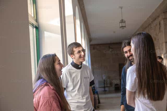 Sacerdote joven ríe con jóvenes - Banco de imágenes católicas