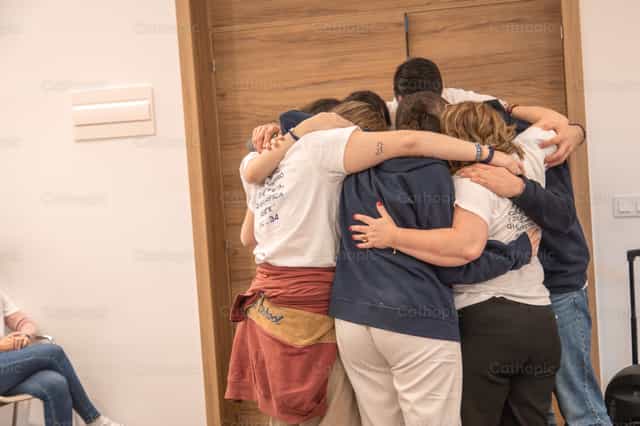 Jóvenes abrazados orando juntos en iglesia - Banco de imágenes católicas - Fotografía por Yandry Fernández Perdomo