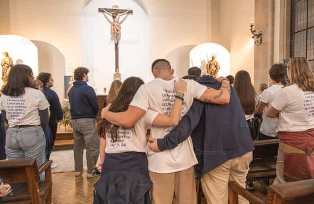 Jovens abraçando enquanto olham para o altar durante a Missa - Imagens católicas de stock