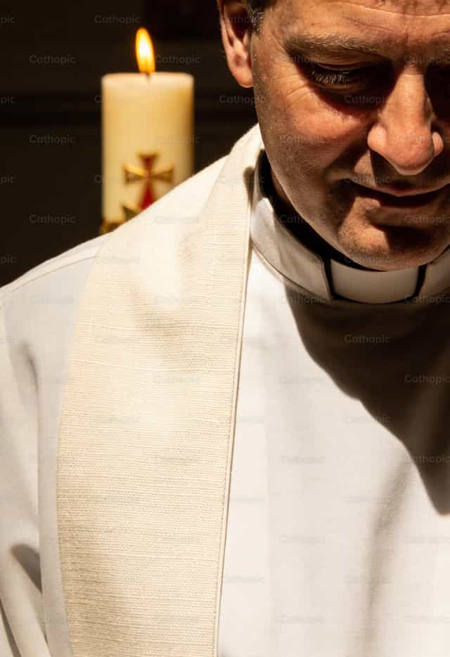 Priest wearing a white chasuble and holding a Paschal candle - Catholic stock images