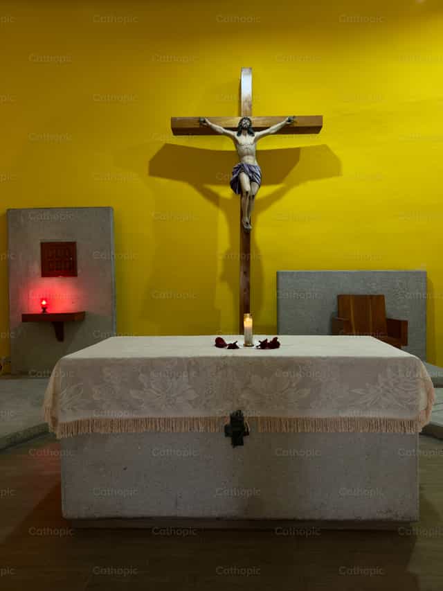 Ein Kruzifix auf einem Altar, in warmes Licht getaucht in einer Kirche - Katholische Stockfotos