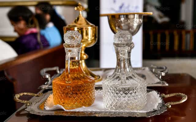 Jarras de aceite y vino sobre una bandeja en el altar durante la misa - Banco de imágenes católicas