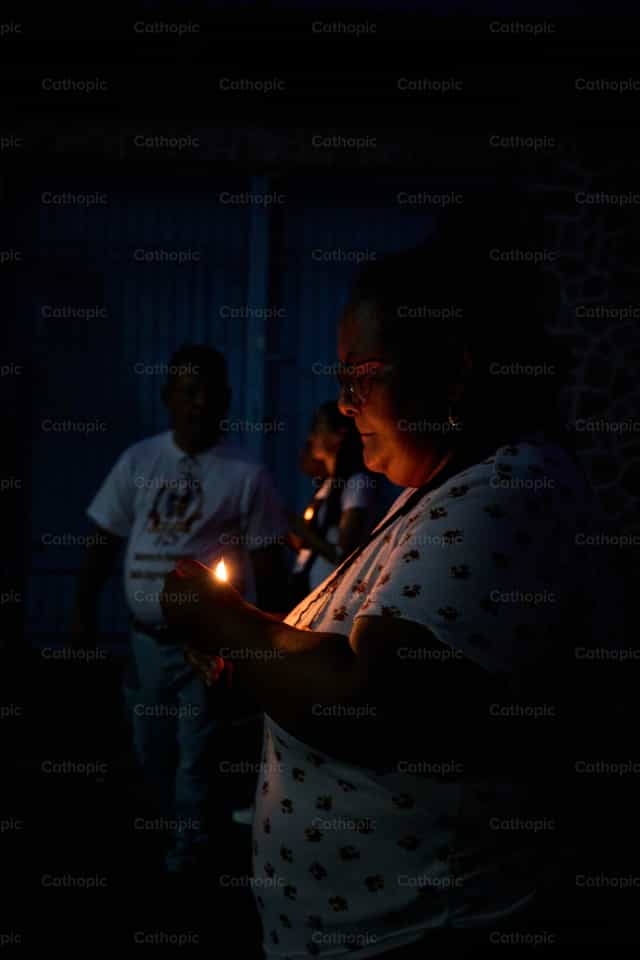 Prayer vigil: A believer with a lit candle at night - Catholic stock images