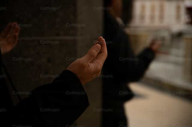 Hands clasped in prayer in church - Catholic stock images - Photo by Carolina BR