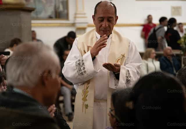 Sacerdote bendiciendo unos rosarios - Banco de imágenes católicas - Fotografía por Carolina BR
