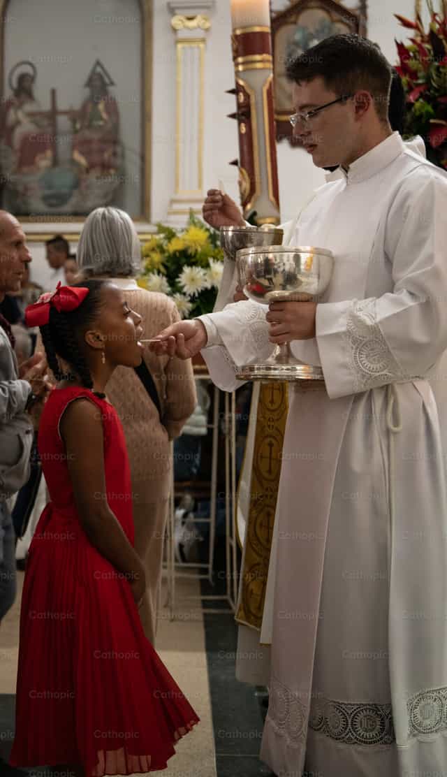 Niña recibiendo la comunión en misa - Banco de imágenes católicas - Fotografía por Carolina BR