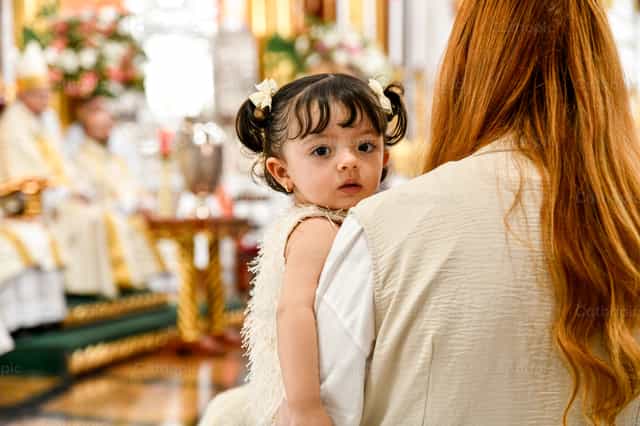 Ein Mädchen, das während der Eucharistiefeier gehalten wird - Katholische Stockfotos - Foto von Carolina BR