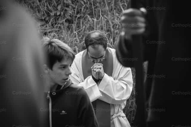 Sacerdote rezando de rodillas en la iglesia - Banco de imágenes católicas - Fotografía por Yandry Fernández Perdomo
