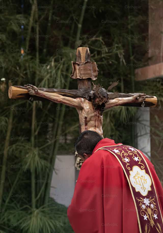 Sacerdote inclinado ante el crucificado - Banco de imágenes católicas