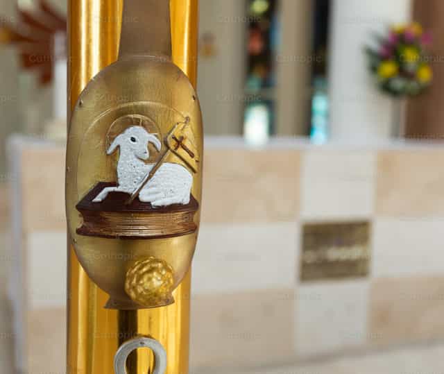 Candela battesimale con simbolo dell’Agnus Dei in un ambiente dorato di chiesa - Immagini stock cattoliche - Foto di Antonio Gravante