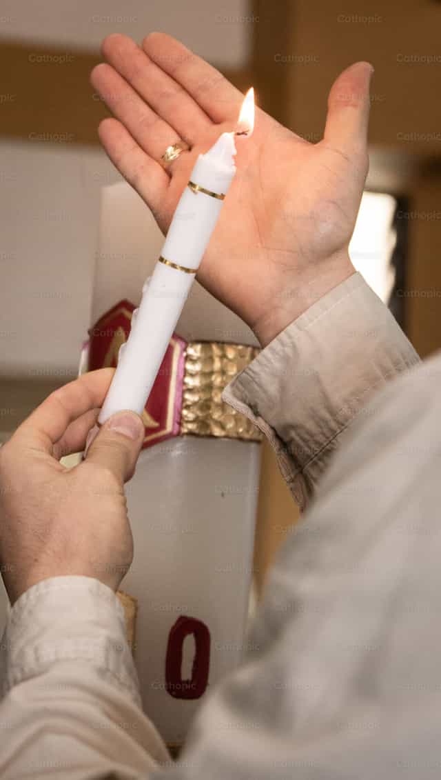 Vela de bautismo encendida en la mano - Banco de imágenes católicas