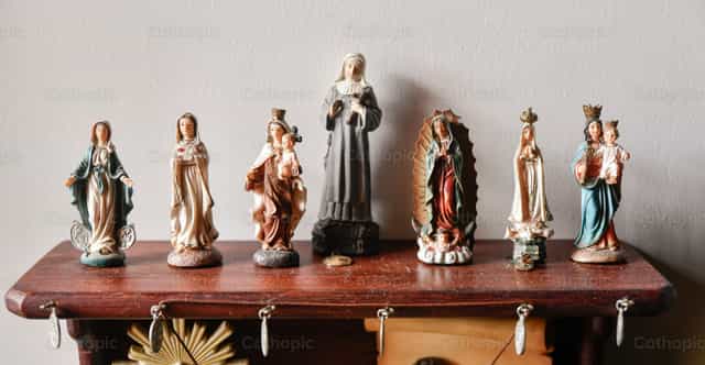 Estatuas devocionales católicas expuestas sobre soportes de madera - Banco de imágenes católicas - Fotografía por Carolina BR