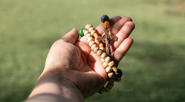A wooden rosary held in the hand - Catholic stock images - Photo by Carolina BR
