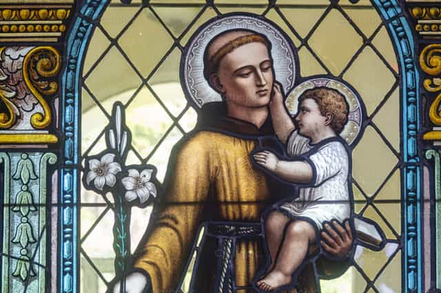Santo António de Pádua segurando o Menino Jesus Cristo - Imagens católicas de stock