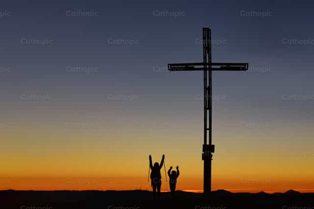 Mom with child on top of the mountain near the cross raise their - Catholic stock images - Photo by Michelangelo Oprandi