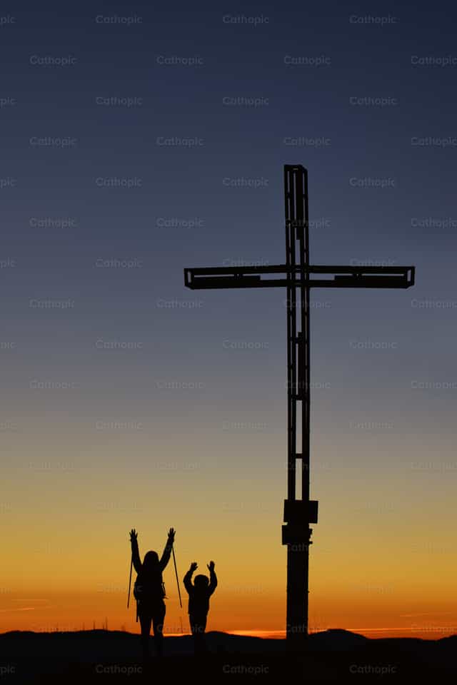 Mom with child on top of the mountain near the cross raise their - Catholic stock images - Photo by Michelangelo Oprandi