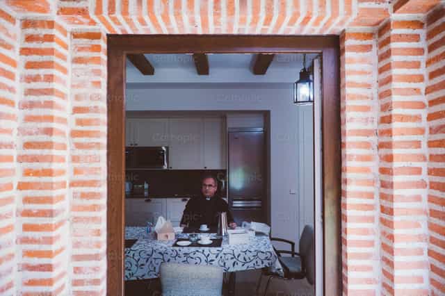 Sacerdote esperando los alimentos al mediodia - Banco de imágenes católicas - Fotografía por Almures Studio